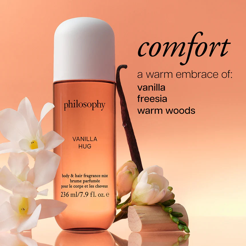 Philosophy Vanilla Hug fragrance bottle with vanilla bean and flowers on a peach background