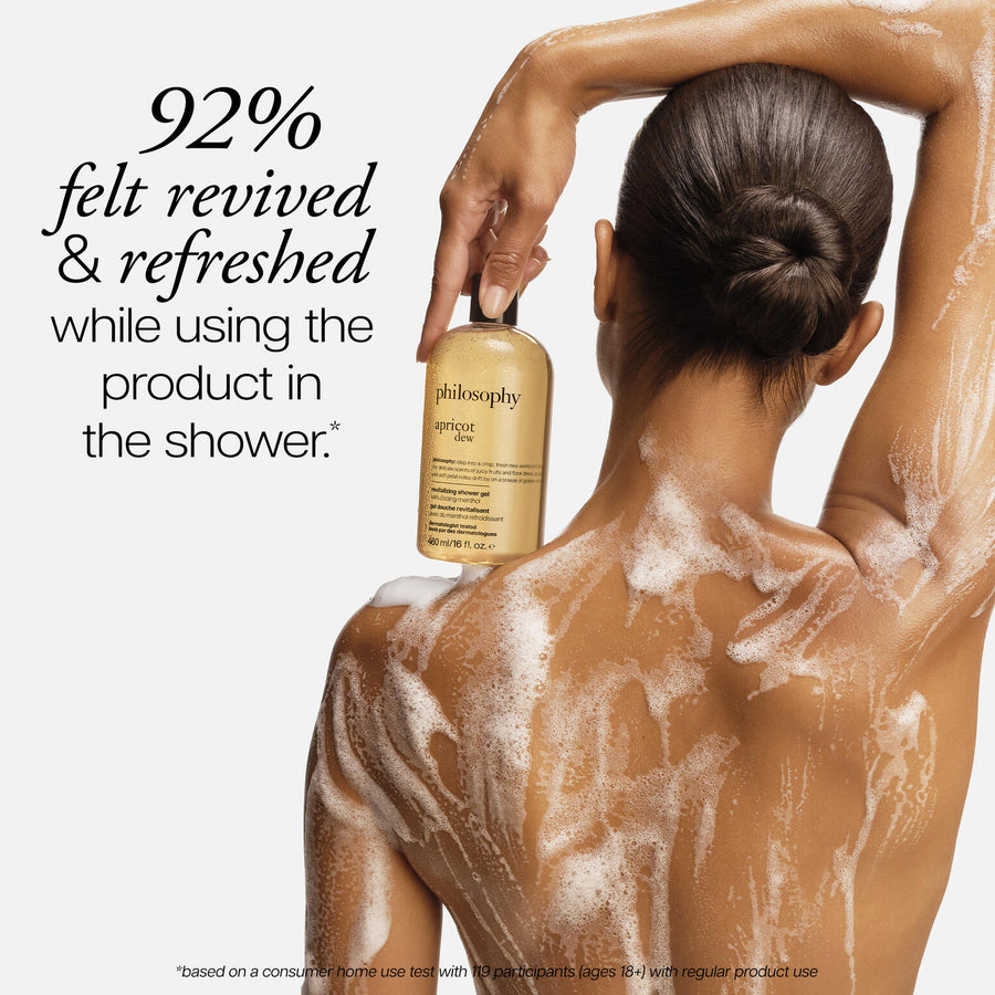 Woman with soap suds on her back holding a bottle of philosophy product.