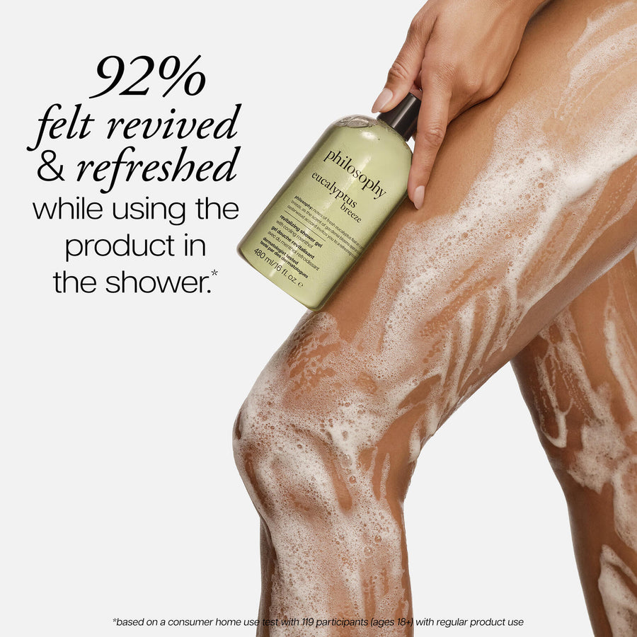 Person using a bottle of Philosophy eucalyptus shower gel on their legs with text about product satisfaction.