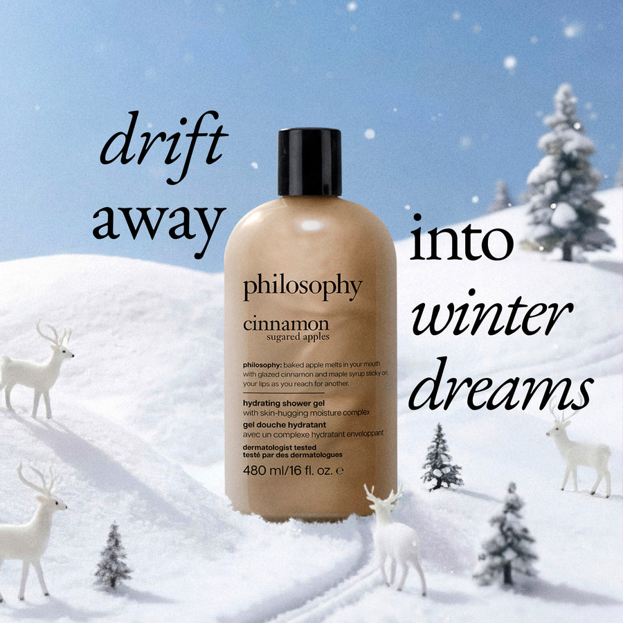 A bottle of Philosophy Cinnamon Sugar Apple Hydrating Shower Gel stands in a snowy winter scene with white deer and small pine trees. Large text reads 'drift away into winter dreams' against a blue sky background.